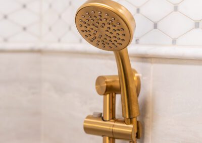 gold shower head with accent tile in renovated shower