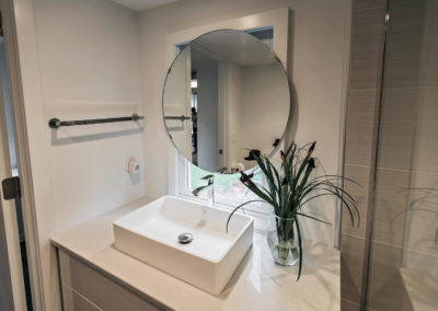 bathroom vanity with raised sink and circular mirror