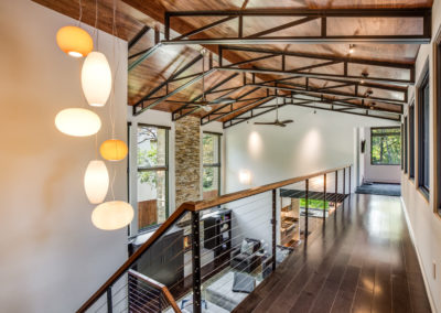 balcony lined upper overlook of living room with modern hanging light fixture