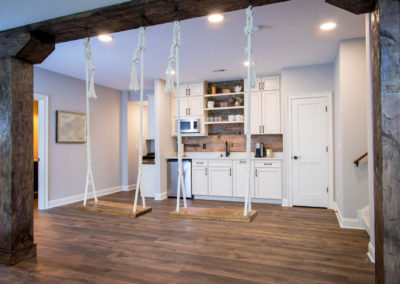 renovated basement with half kitchen and custom indoor swings