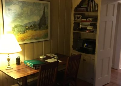 dimly lit library with desk and built-in bookshelf