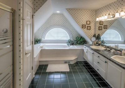 dated master bathroom with black tile floor and wallpaper before remodel