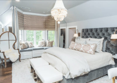 bedroom with gray velvet headboard and chandelier