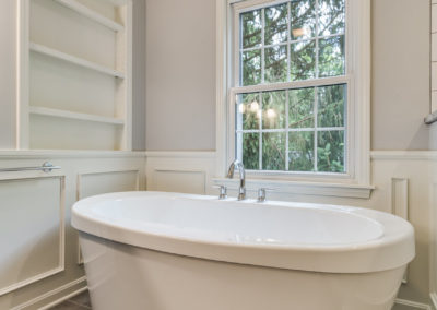 freestanding white soaker tub next to window