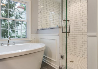 freestanding white tub next to subway tile shower