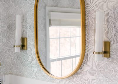 Gold Oval Mirror and Sconces with Patterned Wallpaper