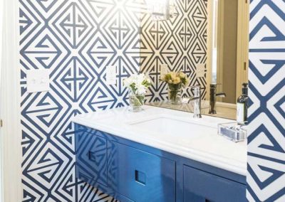 bathroom with blue wall mounted vanity and geometric blue wallpaper