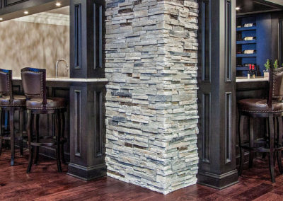 custom basement bar with wraparound seating and stone wall